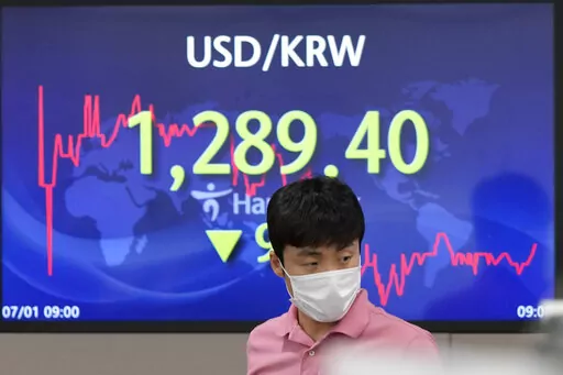 A currency trader walks by the screen showing the foreign exchange rate between U.S. dollar and South Korean won at a foreign exchange dealing room in Seoul, South Korea, Friday, July 1, 2022. Asian benchmarks were mostly lower on Friday, echoing a decline on Wall Street, after a quarterly report by Japan’s central bank rekindled worries about the world’s third largest economy. (AP Photo/Lee Jin-man)