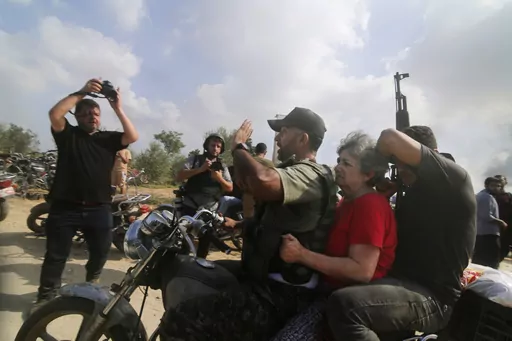 Palestinians transport a captured Israeli civilian, Adina Moshe, from her home in Kibbutz Nir Oz to the Gaza Strip, Oct. 7, 2023. The 72-year-old Israeli woman held captive by Hamas militants for nearly 50 days told an Israeli TV channel Wednesday, Jan. 24, 2024, that she was held at length in a dark, humid tunnel where she met Hamas’ leader and helped pass the time with a makeshift lecture series by her knowledgeable fellow hostages. (AP Photo, File)