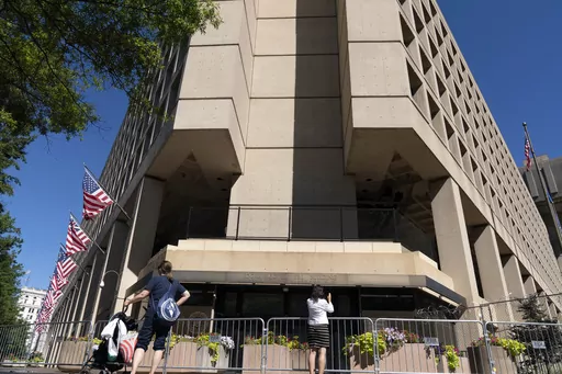 People take photos of the FBI building headquarters in Washington, Aug. 13, 2022. A federal judge in Washington is weighing whether to hold in contempt Catherine Herridge, a veteran journalist who has refused to identify her sources for stories about a Chinese scientist who was investigated by the FBI but never charged. (AP Photo/Jose Luis Magana, File)