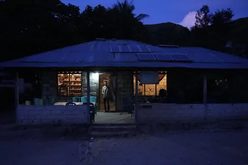 Bara Kilimandang stands at the door of his house whose electricity comes from solar energy in Walatungga on Sumba Island, Indonesia, Tuesday, March 21, 2023. In Indonesia's far-east island, off-grid solar is lighting up lives for residents still living out of reach of the country's national electricity provider. (AP Photo/Dita Alangkara)
