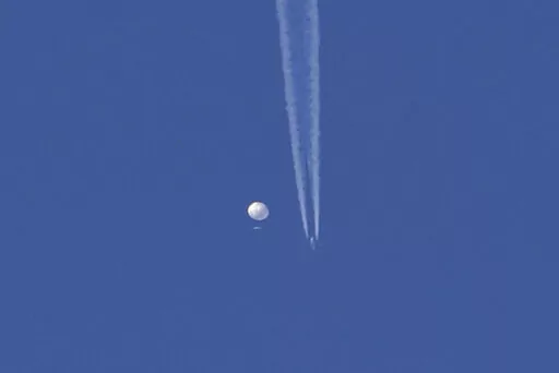 In this photo provided by Brian Branch, a large balloon drifts above the Kingstown, N.C. area, with an airplane and its contrail seen below it. The United States says it is a Chinese spy balloon moving east over America at an altitude of about 60,000 feet (18,600 meters), but China insists the balloon is just an errant civilian airshipused mainly for meteorological research that went off course due to winds and has only limited “self-steering” capabilities. (Brian Branch via AP)