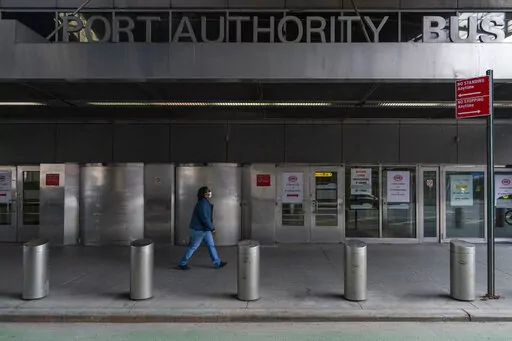 A pedestrian passes the 9th Avenue shuttered doors of the Port Authority Bus Terminal, Friday, Jan. 22, 2021, in New York. The police agency that patrols New York City’s main bus terminal has agreed to stop sending plainclothes officers into its public bathrooms to try and catch people propositioning strangers for sex, a type of sting long criticized by activists as a discriminatory relic of an era of crackdowns predominantly aimed at gay men. (AP Photo/Mary Altaffer, File)