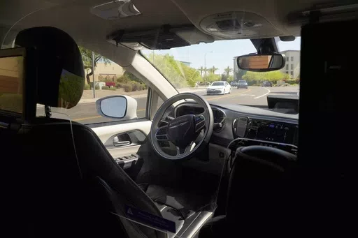 A Waymo minivan moves along a city street as an empty driver's seat and a moving steering wheel drive passengers during an autonomous vehicle ride, on April 7, 2021, in Chandler, Ariz. The U.S. government's highway safety agency has opened another investigation of automated driving systems, this time into crashes involving Waymo's self-driving vehicles. The National Highway Traffic Safety Administration posted documents detailing the probe on its website early Tuesday after getting 22 reports of