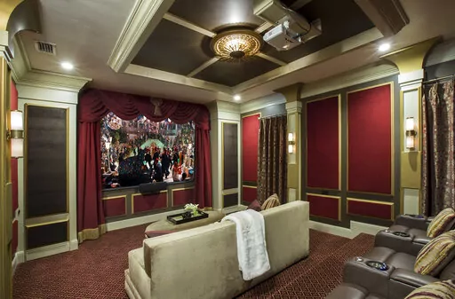 This image provided by John McClain Design shows a home theater with red velvet on the wall panels. The 'champagne-hued velvet' is on the big couch in foreground. For an Orlando, FL project, designer John McClain and his client wanted to evoke an Art Deco aesthetic, yet still design a functional state-of-the-art home theater. "We upholstered portions of the walls with red velvet inside of wooden accent panels to gain the hard-to-soft-surface-ratio that would normally be accomplished with acousti