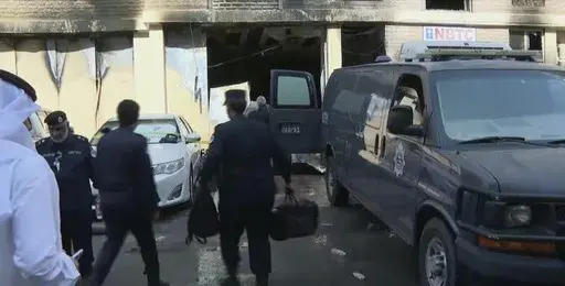 Rescuers arrive at the site of a building that caught fire in Kuwait, Wednesday, June 12, 2024. At least 41 people died when a fire swept through a building that housed workers in Kuwait early Wednesday, and officials said the blaze appeared to be linked to code violations. (Kuwait TV via AP)