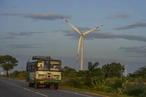 A bus drives past a windmill farm in Anantapur district, Andhra Pradesh, India, Sept 14, 2022. The key priority for India at the upcoming U.N. climate conference will be how to pay for the transition away from fossil fuels for energy and industries to meet temperature limit targets, according to a senior official who'll be part of the negotiations. (AP Photo/Rafiq Maqbool)