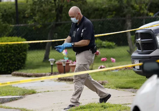 An investigator walks out of a home along Broadway Street, Sunday, June 25, 2023, in Newton, Mass. A couple celebrating their 50th wedding anniversary were stabbed to death, along with another family member, in what law enforcement officials said was probably a random attack. (Jessica Rinaldi/The Boston Globe via AP)