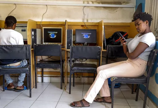 A customer uses the Wi-Fi on her mobile phone at an internet cafe in the low-income Kibera neighborhood of Nairobi, Kenya on Sept. 29, 2021. Facebook has failed to catch Islamic State group and al-Shabab extremist content in posts aimed at East Africa as the region remains under threat from violent attacks and Kenya prepares to vote in a closely contested national election, according to a new study released Wednesday, June 15, 2022. (AP Photo/Brian Inganga, File)