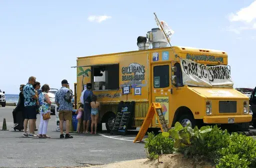 People line up at a food truck parked near Waikiki Beach in Honolulu, Monday, May 23, 2022. A COVID surge is under way that is starting to cause disruptions as schools wrap up for the year and Americans prepare for summer vacations. Case counts are as high as they've been since mid-February and those figures are likely a major undercount because of unreported home tests and asymptomatic infections. But the beaches beckoned and visitors have flocked to Hawaii, especially in recent months. (AP Pho