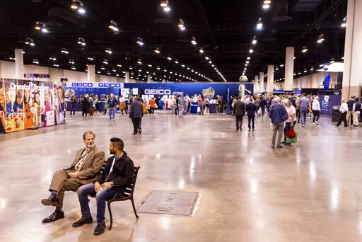 Two men take a break on a bench during the Berkshire Hathaway 2022 Annual Shareholders Meeting weekend at the CHI Health Center in Omaha, Neb., Friday, April 29, 2022. (Anna Reed/Omaha World-Herald via AP)