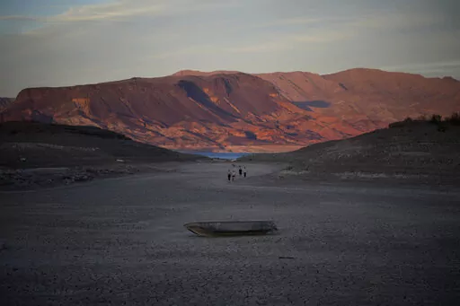 A formerly sunken boat sits on cracked earth hundreds of feet from what is now the shoreline on Lake Mead at the Lake Mead National Recreation Area, Monday, May 9, 2022, near Boulder City, Nev. Lake Mead is receding and Sin City is awash with mob lore after a second set of human remains emerged within a week from the depths of the drought-stricken Colorado River reservoir just a short drive from the Las Vegas Strip.  (AP Photo/John Locher)