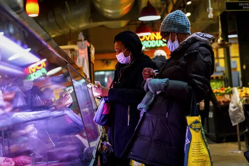 Customers wearing face masks to protect against the spread of the coronavirus shop at the Reading Terminal Market in Philadelphia, Wednesday, Feb. 16, 2022.  Philadelphia city officials lifted the city's vaccine mandate for indoor dining and other establishments that serve food and drinks, but an indoor mask mandate remains in place. Philadelphia Public Health officials announced that the vaccine mandate was lifted immediately Wednesday. (AP Photo/Matt Rourke)