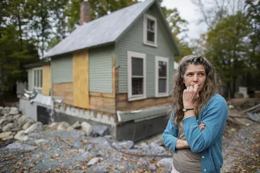 Jenny Mackenzie stands outside her flood-ravaged house in Peacham, Vt. on Sept. 23, 2024. (AP Photo/Dmitri Beliakov)