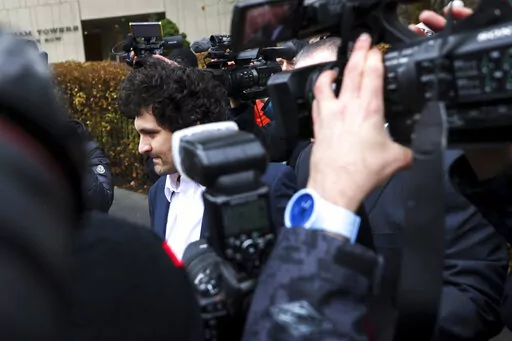 FTX founder Sam Bankman-Fried, center, is escorted to his car from the U.S. District Court in Manhattan, Thursday, Dec. 22, 2022, in New York. A judge agreed to a request by prosecutors to keep it secret that two of Bankman-Fried's executive associates had turned against him so that the cryptocurrency entrepreneur would agree not to fight extradition from the Bahamas to the United States, according to transcripts of plea deals made public Friday, Dec. 23, 2022. (AP Photo/Julia Nikhinson)