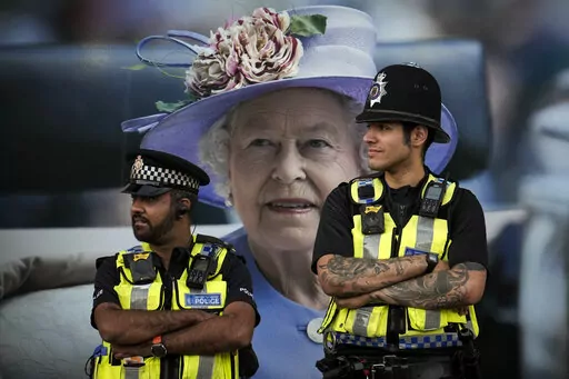 Police officers are backdropped by a photograph of Queen Elizabeth II in London, Friday, Sept.16, 2022. The Queen will lie in state in Westminster Hall for four full days before her funeral on Monday Sept. 19.(AP Photo/Vadim Ghirda)