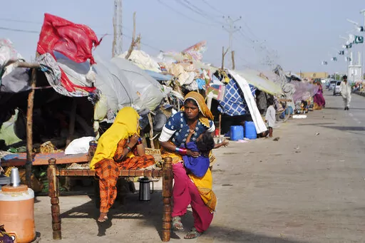 Displaced families who fled their flood-hit homes take refuge along a roadside in Jamshoro, southern Sindh province, Pakistan, Friday, Sept. 16, 2022. The devastating floods affected over 33 million people and displaced over half a million people who are still living in tents and make-shift homes. The water has destroyed 70% of wheat, cotton and other crops in Pakistan. (AP Photo/Pervez Masih)