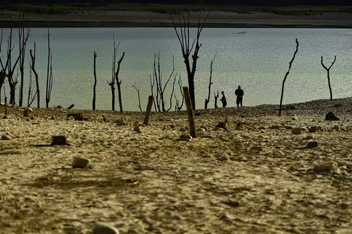 People walk close to the border at Yesa's reservoir affected by drought, on a sunny summer day in Yesa, around 55 kilometers (34,17 miles), from Pamplona, northern Spain, Sept. 14, 2022. Widespread drought that dried up large parts of Europe, the United States and China this past summer was made 20 times more likely by climate change, according to a new study. (AP Photo/Alvaro Barrientos)