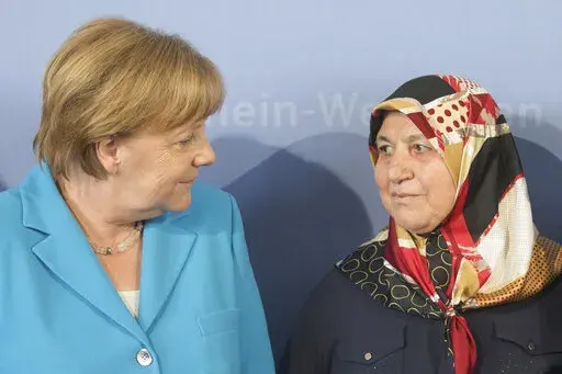 German Chancellor Angela Merkel, left, talks to Mevlude Genc, mother, grandmother and aunt of the victims, in Duesseldorf, western Germany, Tuesday, May 29, 2018 during a commemoration of the 25th anniversary of a firebombing in which five Turks were killed in Solingen. Mevlude Genc, who worked for reconcilition after five members of her family were killed in a racist attack that shook Germany in the early 1990s, has died. (Rolf Vennenbernd/dpa via AP, File)