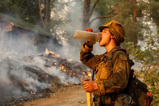 Firefighter Trapper Gephart of Alaska's Pioneer Peak Interagency Hotshot crew takes a drink while battling the Mosquito Fire in the Volcanoville community of El Dorado County, Calif., on Friday, Sept. 9, 2022. (AP Photo/Noah Berger)