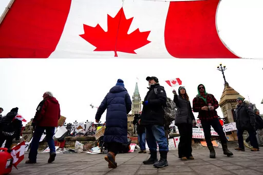 A Canada flag is hung between traffic light posts in front of Parliament Hill during a protest against COVID-19 restrictions in Ottawa, on Friday, Feb. 11, 2022.  Ontario’s premier declared a state of emergency Friday in reaction to the truck blockades in Ottawa and at the U.S. border and threatened heavy penalties against those who interfere with the free flow of goods and people. (Justin Tang /The Canadian Press via AP)