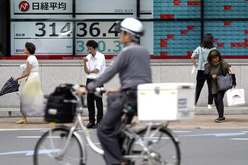 People stand near an electronic stock board showing Japan's Nikkei 225 index at a securities firm Thursday, Aug. 17, 2023, in Tokyo. Asian stocks followed Wall Street lower Thursday after notes from a U.S. Federal Reserve meeting dented hopes interest rate hikes are finished. (AP Photo/Eugene Hoshiko)