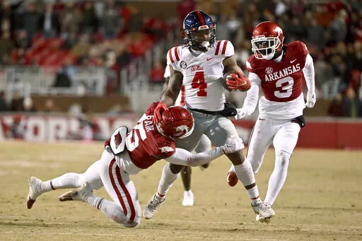 Mississippi running back Quinshon Judkins (4) is tackled by Arkansas defenders Simeon Blair (15) and Dwight McGlothern (3) during the first half of an NCAA college football game Saturday, Nov. 19, 2022, in Fayetteville, Ark. (AP Photo/Michael Woods)
