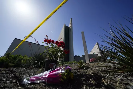 Flowers sit near crime scene tape at Geneva Presbyterian Church, Tuesday, May 17, 2022, in Laguna Woods, Calif., after a fatal shooting at the church. David Chou, of Las Vegas, suspected of killing one person and wounded five others when he shot up a Southern California church luncheon last year, has been charged with dozens of federal hate crimes in connection with the attack, which investigators say was motivated by political hatred of Taiwan, according to n indictment released Thursday, May 1