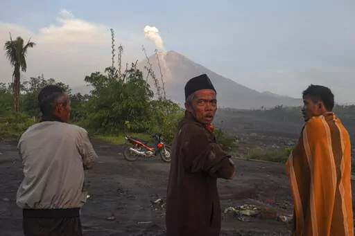 People watch as Mount Semeru spews volcanic materials from it crater in Lumajang, East Java, Indonesia, Monday, Dec. 5, 2022. Improved weather conditions Monday allowed rescuers to resume evacuation efforts and a search for possible victims after the highest volcano on Indonesia's most densely populated island erupted, triggered by monsoon rains. (AP Photo/Dicky Bisinglasi)