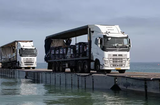 Trucks loaded with humanitarian aid from the United Arab Emirates and the United States Agency for International Development cross the Trident Pier before entering the beach in Gaza, May 17, 2024. (Staff Sgt. Malcolm Cohens-Ashley/U.S. Army Central via AP)
