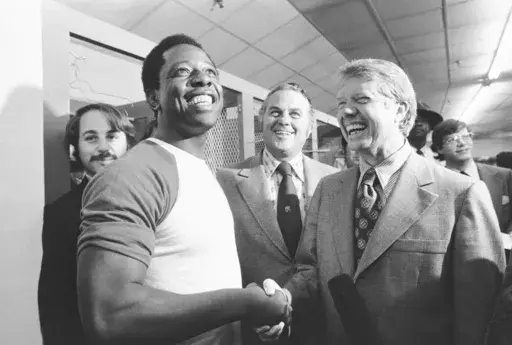 Georgia Gov. Jimmy Carter, right, and Delaware Gov. Sherman Tribbitt say hello to Atlanta Braves Hank Aaron, left, following a rain canceled game with the Los Angeles Dodgers in Atlanta, Ga., Sept. 27, 1973. (AP Photo, File)