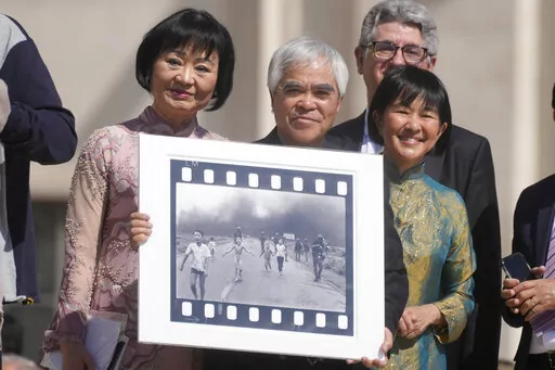Pulitzer Prize-winning photographer Nick Ut, center, flanked by Kim Phuc, left, holds the" Napalm Girl", his Pulitzer Prize winning photo as they wait to meet with Pope Francis during the weekly general audience in St. Peter's Square at The Vatican, Wednesday, May 11, 2022. Ut and UNESCO Ambassador Kim Phuc are in Italy to promote the photo exhibition "From Hell to Hollywood" resuming Ut's 51 years of work at the Associated Press, including the 1973 Pulitzer-winning photo of Kim Phuc fleeing her