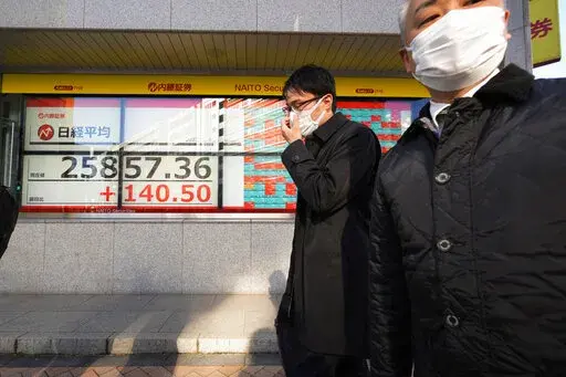 Businessmen walk by monitors showing Tokyo's Nikkei 225 index at a securities firm in Tokyo, Thursday, Jan. 5, 2023. Asian shares are mostly higher following a rally on Wall Street as investors assessed minutes from the Federal Reserve’s latest meeting of policymakers and welcomed encouraging data on U.S. jobs. (AP Photo/Hiro Komae)