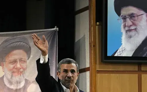 Iran's hard-line former President Mahmoud Ahmadinejad waves to the media as he leaves at the conclusion of a press briefing beside portraits of the Supreme Leader Ayatollah Ali Khamenei, top right, and the late President Ebrahim Raisi after registering his name as a candidate for the June 28 presidential election at the Interior Ministry, in Tehran, Iran, Sunday, June 2, 2024. Ahmadinejad registered Sunday as a possible candidate for the presidential election, seeking to regain the country's top