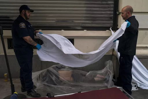 Forensic assistant Laurentiu Bigu, left, and investigator Ryan Parraz from the Los Angeles County coroner's office cover the body of a homeless man found dead on a sidewalk in Los Angeles on April 18, 2022. The 60-year-old man died from the effects of methamphetamine, according to his autopsy report. Drug overdose deaths in the U.S. went up slightly in 2022 after two big leaps during the pandemic. (AP Photo/Jae C. Hong, File)