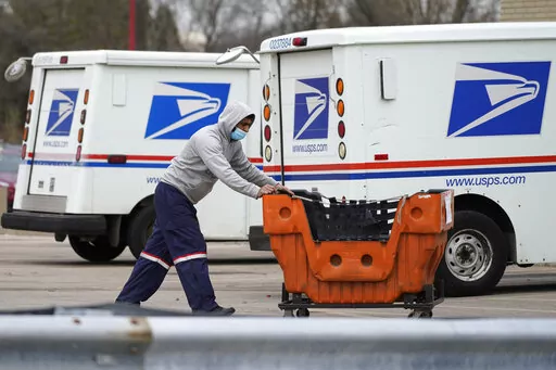 A United States Postal Service employee works outside a post office in Wheeling, Ill., Dec. 3, 2021.  The nation’s major shipping companies are in the best shape to get holiday shoppers’ packages delivered on time since the start of the pandemic, suggesting a return to normalcy. (AP Photo/Nam Y. Huh, File)