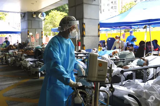 Patients in hospital beds wait in a temporary holding area outside Caritas Medical Centre in Hong Kong , Wednesday, March 2, 2022. Some people are forced to wait outside the hospital due to it currently being overloaded with possible COVID-infected patients. (AP Photo/Kin Cheung)