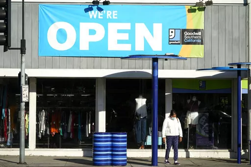 In this June 9, 2021, file photo, a sign announces that a Goodwill store is open in Santa Monica, Calif. Thrifting is hot, and Goodwill finds are cool again. But while we’re thrilled to find the perfect throwback tee for our own closet, gifting used goods still carries a stigma for some. It shouldn’t. Secondhand gifts are better for your wallet, your community and the environment. Buying a thrifted sweatshirt, jacket or vase keeps it from landing in a heap at the dump. (AP Photo/Marcio Jose 