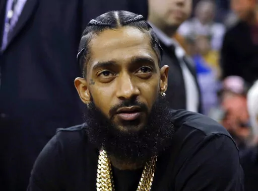 Rapper Nipsey Hussle attends an NBA basketball game between the Golden State Warriors and the Milwaukee Bucks in Oakland, Calif., March 29, 2018. Eric R. Holder Jr., who was convicted last year of fatally shooting Hussle in 2019, is scheduled to be sentenced Wednesday, Feb. 22, 2023, in a Los Angeles courtroom. (AP Photo/Marcio Jose Sanchez, File)