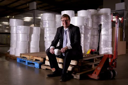 Jim Schmersahl, owner of Halcyon Shades, poses with material used in making N-95 masks Friday, March 18, 2022, in University City, Mo. Halcyon is small company that normally makes window shades, but when the pandemic hit, its sales plummeted. Halcyon applied for the state grants to make PPE as a way to try to keep its employees at work and keep the company afloat. (AP Photo/Jeff Roberson)