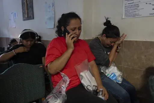 Holding a Border Patrol-issued plastic bag containing her belongings, Mexican migrant Ana Ruiz, right, wipes her tears while talking to a family member at the San Juan Bosco migrant shelter in Nogales, Mexico, Tuesday, June 25, 2024, after she was deported back to her homeland from the U.S. The asylum halt, which took effect June 5 and has led a 40% decline in arrests for illegal crossings, applies to all nationalities but falls hardest on nationalities most susceptible to deportation _ specific