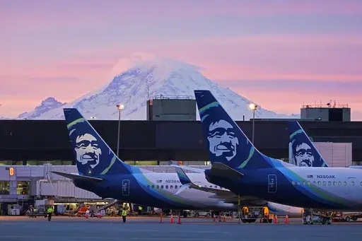 Alaska Airlines planes are shown parked at gates with Mount Rainier in the background at sunrise, March 1, 2021, at Seattle-Tacoma International Airport in Seattle. (AP Photo/Ted S. Warren, File)