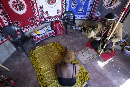 Traditional healer, Shadrack Mashabane, consults with his wife before testing her for HIV in Bushbuckridge, South Africa, Thursday, May 9, 2024. While South Africa has made strides in fighting HIV, prevalence remains high and stigma is widespread in many communities with researchers hoping the relationship of trust between villagers and traditional healers will bring more people to HIV testing, counseling and care. (AP Photo/Themba Hadebe)