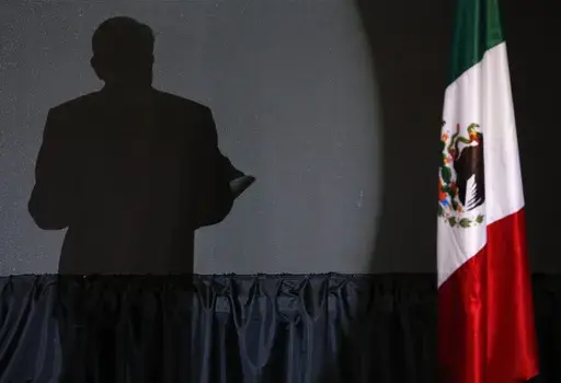 The shadow of presidential candidate Andres Manuel Lopez Obrador, founder of the ruling party, Morena, is cast on a screen as he gives his first victory speech at his campaign headquarters at the Hilton hotel in Mexico City, late July 1, 2018. (AP Photo/Marco Ugarte, File)