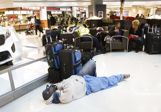 A man sleeps on the terminal floor at Hartfield-Jackson Atlanta International Airport on Dec. 18, 2017, in Atlanta. Transportation Secretary Pete Buttigieg has warned airlines that his department could draft new rules around passenger rights if the carriers don’t give more help to travelers trapped by flight cancellations and delays. The Transportation Department on Friday, Aug. 19, 2022, released a copy of the letters, which it said were sent to CEOs of the major U.S. airlines, their regional