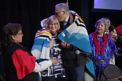 Washington Gov. Jay Inslee, second from right, kisses his wife Trudi, after they were presented a blanket in a ceremony after Inslee signed a bill that creates a first-in-the-nation statewide alert system for missing Indigenous people — particularly women, Thursday, March 31, 2022, in Quil Ceda Village, near Marysville, Wash., north of Seattle. The law creates a system similar to Amber Alerts, which are used for missing children in many states. (AP Photo/Ted S. Warren)