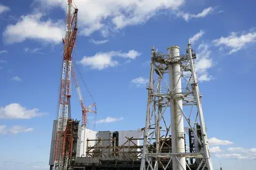The damaged Unit 1 reactor, back, and the exhaust stack shared by the Unit 1 and 2 reactors are seen at the Fukushima Daiichi nuclear power plant, operated by Tokyo Electric Power Company Holdings (TEPCO), in Okuma town, northeastern Japan on Monday Feb. 20, 2025. (AP Photo/Eugene Hoshiko)