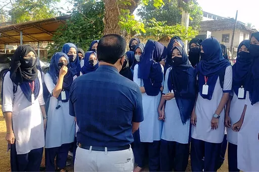 Indian girl students who were barred from entering their classrooms for wearing hijab, a headscarf used by Muslim women, speak to their principal outside the college campus in Udupi, India, Friday, Feb. 4, 2022. Muslim girls wearing hijab are being barred from attending classes at some schools in the southern Indian state of Karnataka, triggering weeks of protests by students. (Bangalore News Photos via AP)