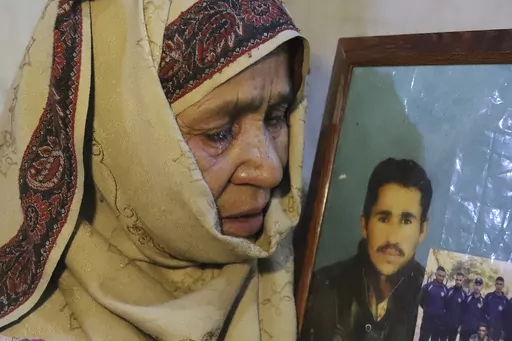 The mother of Mohammed Hassan, a Pakistani porter who died on July 27 during a summit of K2, weeps while she holds a portrait of him at their home in Tasar, a village in the Shigar district in the Gilgit-Baltistan region of northern Pakistan, Saturday, Aug. 12, 2023. An investigation has been launched into the death of a Hassan near the peak of the world's most treacherous mountain, a Pakistani mountaineer said Saturday, following allegations that dozens of climbers eager to reach the summit had