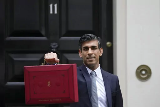 Britain's Chancellor of the Exchequer Rishi Sunak holds up the traditional ministerial red dispatch box as he leaves for the House of Commons to deliver the Budget in London, Oct. 27, 2021. Revelations that Prime Minister Boris Johnson and his staff partied while Britain was in a coronavirus lockdown have provoked public outrage and led some members of his Conservative Party to consider ousting their leader. If they manage to push Johnson out — or if he resigns — the party would hold a leade