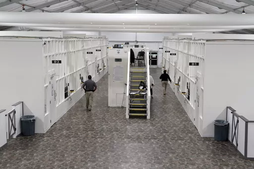 Agents walk among rooms at a Border Patrol holding facility on Dec. 15, 2023, in Tucson, Ariz. U.S. asylum officers were instructed nearly a year ago to apply a higher screening standard on people who cross the border illegally to claim asylum after passing through another country. But they are too understaffed to have much impact. (AP Photo/Gregory Bull, File)
